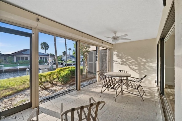 sunroom / solarium featuring ceiling fan and a water view