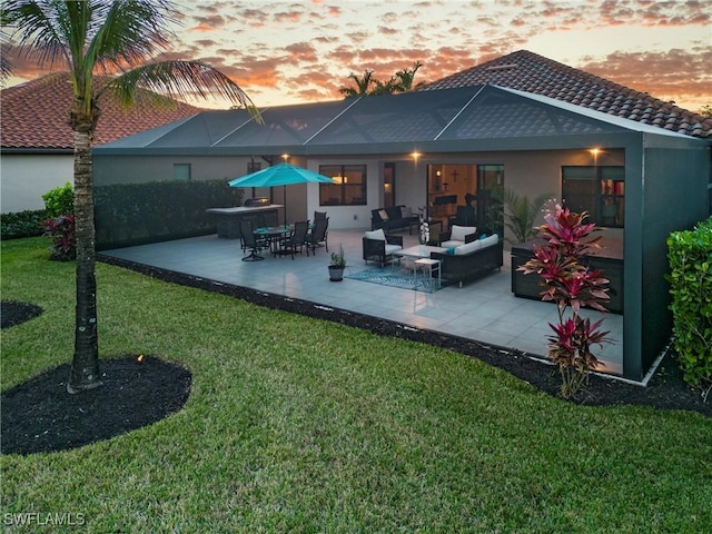 back house at dusk with an outdoor hangout area, a patio, and a yard