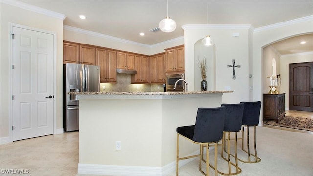 kitchen with a kitchen bar, appliances with stainless steel finishes, tasteful backsplash, light stone counters, and pendant lighting