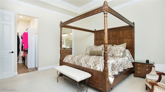 carpeted bedroom featuring ensuite bathroom, a spacious closet, and crown molding