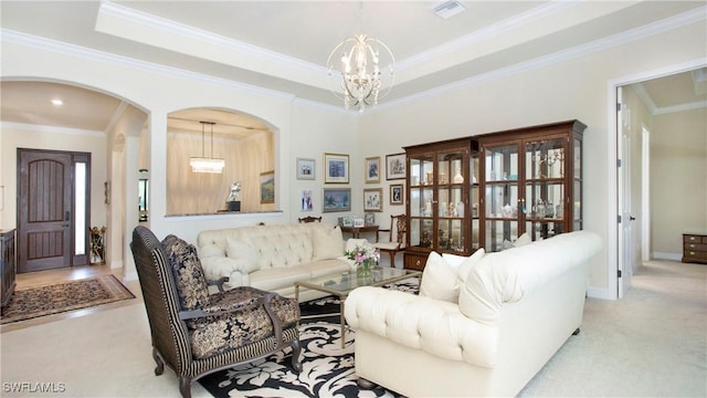 living room with a tray ceiling, crown molding, light colored carpet, and a chandelier