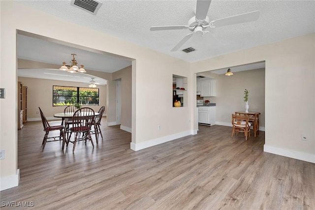 dining room featuring a textured ceiling, light hardwood / wood-style floors, and ceiling fan