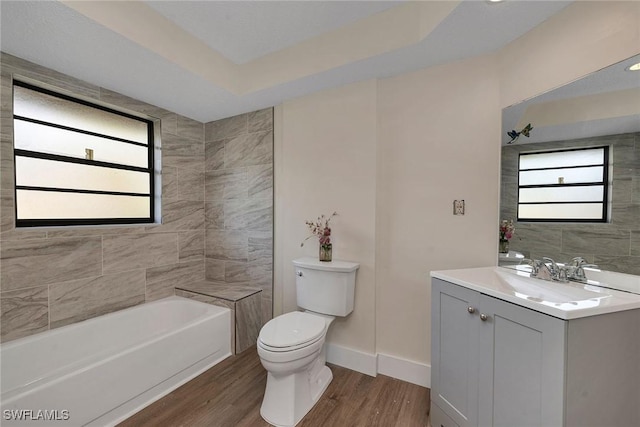 bathroom featuring wood-type flooring, vanity, toilet, and a raised ceiling