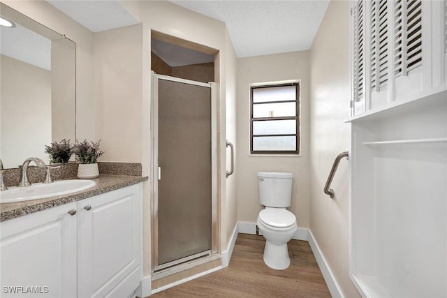 bathroom with hardwood / wood-style floors, vanity, toilet, walk in shower, and a textured ceiling