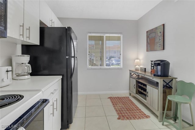 kitchen with light tile patterned floors, white cabinetry, and range with electric stovetop