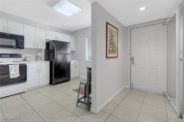 kitchen with light tile patterned floors, white cabinetry, and black appliances