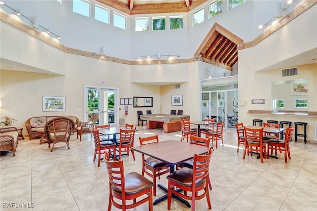 dining space with a high ceiling, light tile patterned floors, and french doors