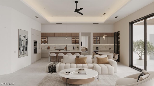 living room featuring ceiling fan and a raised ceiling