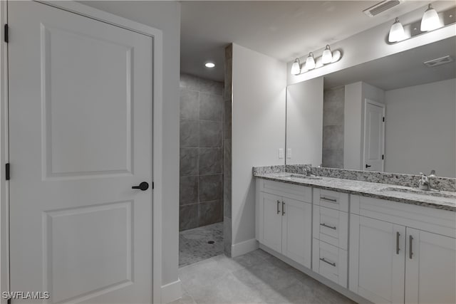 bathroom with tile patterned floors, vanity, and a tile shower