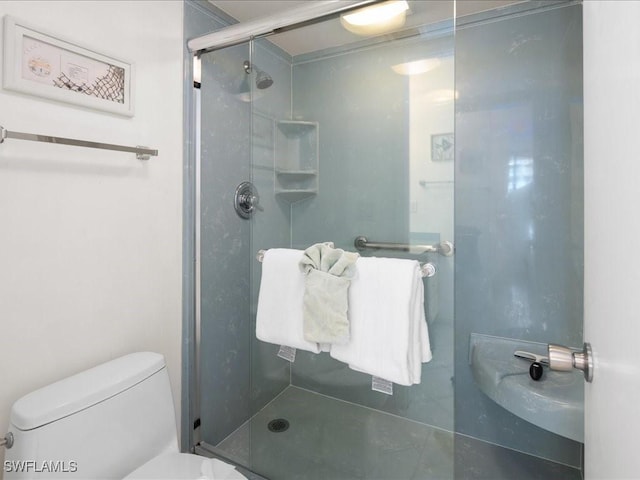 bathroom featuring toilet and a shower with shower door