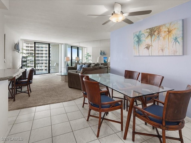 dining room featuring ceiling fan, a wall of windows, and light carpet