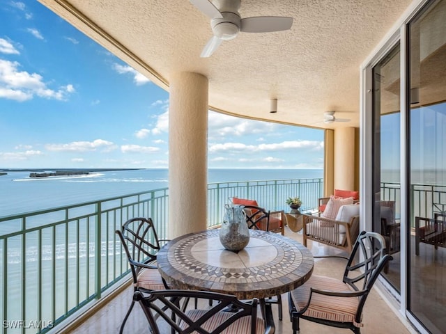 balcony with ceiling fan and a water view