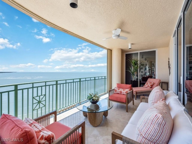 balcony with outdoor lounge area, ceiling fan, and a water view