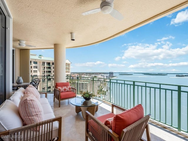 balcony with ceiling fan and a water view