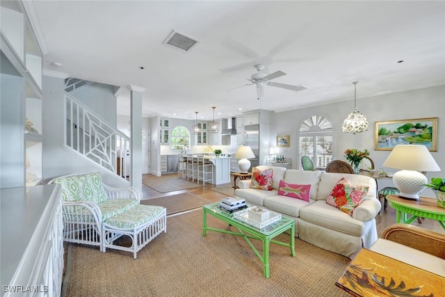 living room featuring ornate columns and ceiling fan with notable chandelier