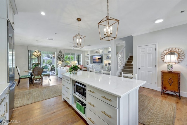 kitchen featuring white cabinets, appliances with stainless steel finishes, a kitchen island, and pendant lighting