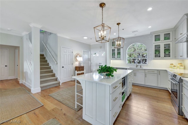 kitchen with a center island, sink, hanging light fixtures, white cabinetry, and stainless steel appliances