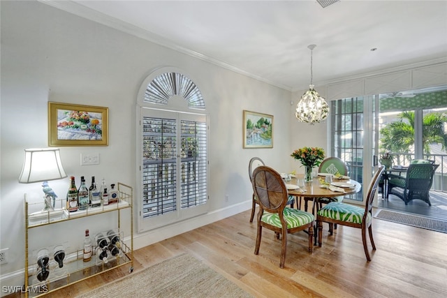 dining room with a notable chandelier, light wood-type flooring, and ornamental molding