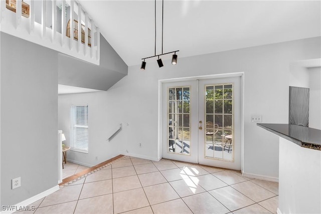 unfurnished dining area featuring french doors, vaulted ceiling, and light tile patterned floors