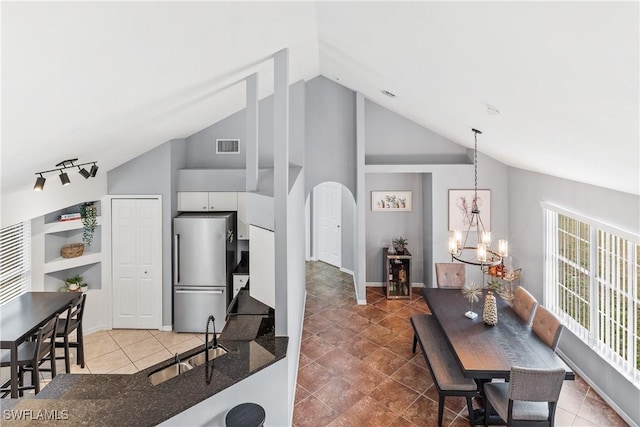 kitchen with sink, white cabinets, lofted ceiling, stainless steel fridge, and pendant lighting