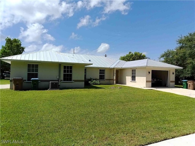 rear view of house with a lawn, cooling unit, and a garage