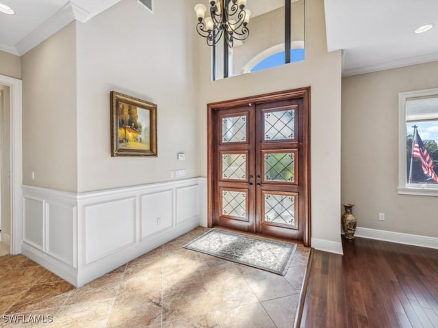 foyer entrance featuring hardwood / wood-style floors, a notable chandelier, crown molding, and french doors