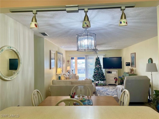 dining space with ceiling fan with notable chandelier and a textured ceiling