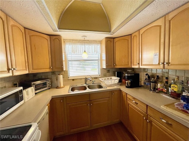 kitchen featuring white microwave, stove, dark wood-type flooring, a tray ceiling, and a sink