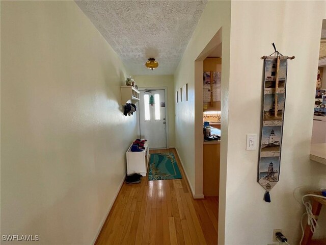 hallway featuring light hardwood / wood-style floors and a textured ceiling