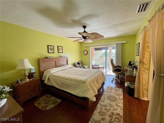 bedroom featuring visible vents, a ceiling fan, dark wood-style floors, access to outside, and a textured ceiling