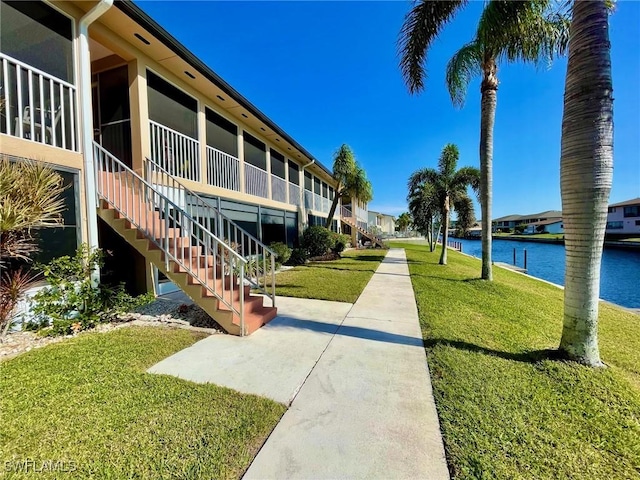 surrounding community with a water view, stairs, and a lawn