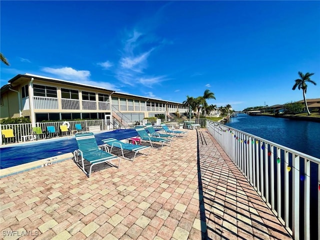 view of property's community with a water view, a patio area, a swimming pool, and fence