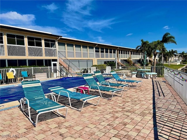 view of swimming pool with stairway, a swimming pool, fence, and a patio