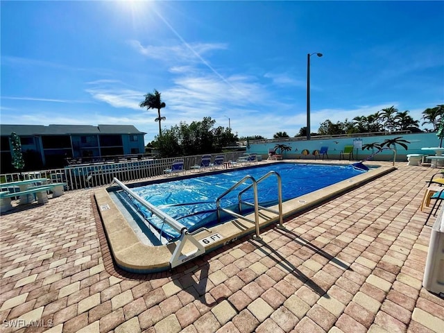 community pool featuring fence and a patio