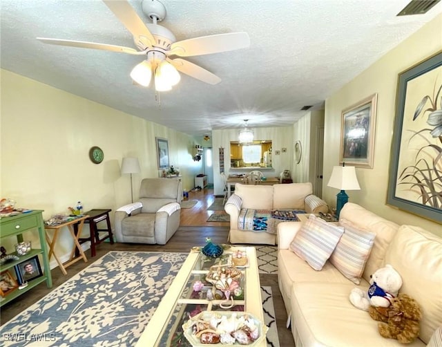 living room featuring a textured ceiling, ceiling fan, wood finished floors, and visible vents