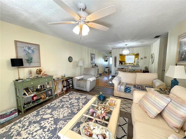 living room featuring hardwood / wood-style flooring, ceiling fan, and a textured ceiling