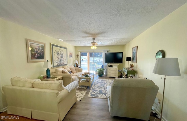 living room featuring ceiling fan, dark wood finished floors, and a textured ceiling