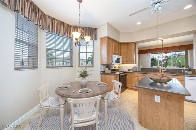 kitchen with sink, decorative light fixtures, white appliances, light tile patterned floors, and ceiling fan with notable chandelier