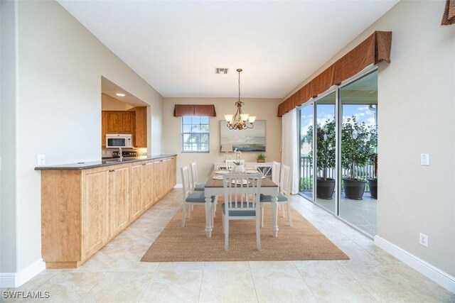 dining area with a notable chandelier, light tile patterned flooring, and a wealth of natural light