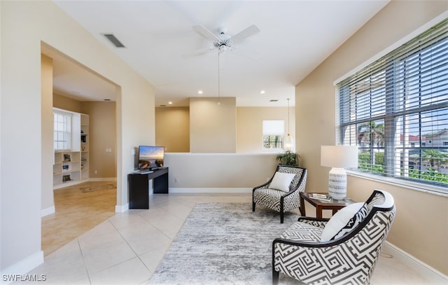 sitting room featuring light tile patterned floors, a wealth of natural light, and ceiling fan