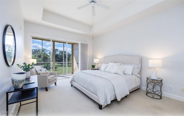 carpeted bedroom featuring ceiling fan, a tray ceiling, and access to exterior