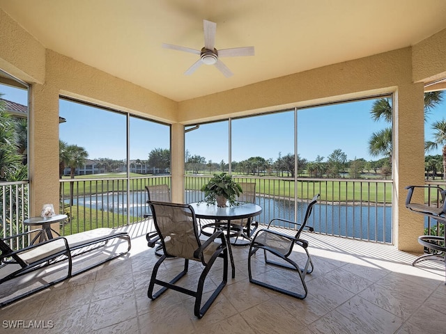 sunroom featuring a water view and ceiling fan