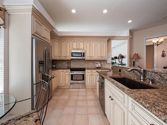 kitchen with tasteful backsplash, dark stone counters, stainless steel appliances, sink, and an inviting chandelier