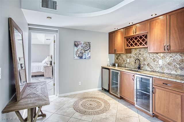 kitchen with light tile patterned floors, light stone countertops, sink, and beverage cooler