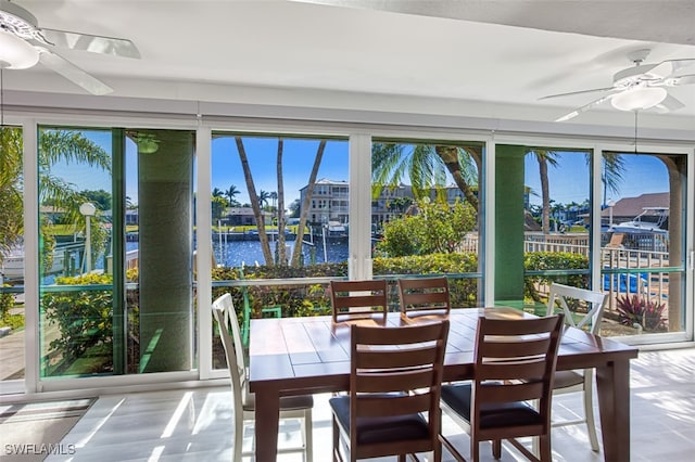 sunroom / solarium featuring ceiling fan, a water view, and a healthy amount of sunlight