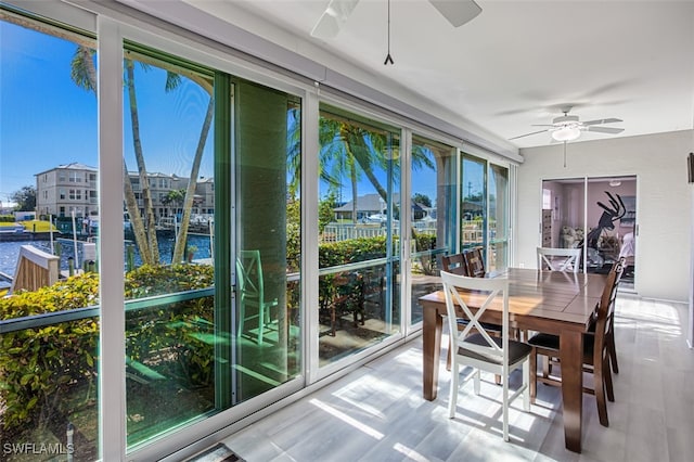 sunroom featuring a water view and ceiling fan