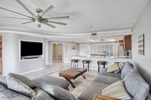 tiled living room with a textured ceiling, a raised ceiling, and sink