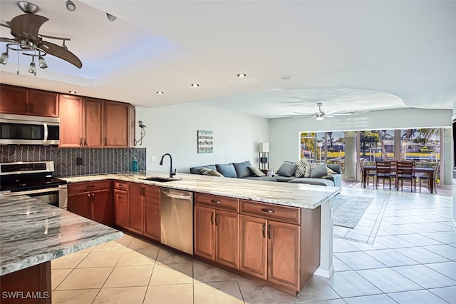 kitchen with sink, tasteful backsplash, light tile patterned flooring, kitchen peninsula, and stainless steel appliances