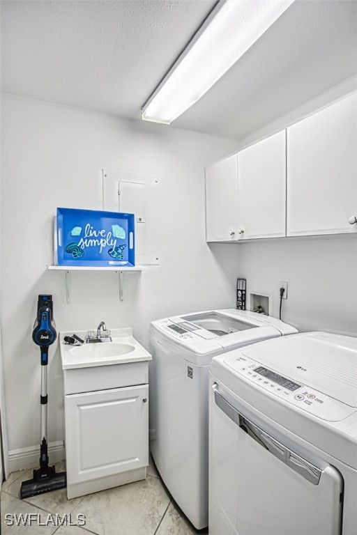 washroom featuring cabinets, light tile patterned floors, sink, and washing machine and clothes dryer