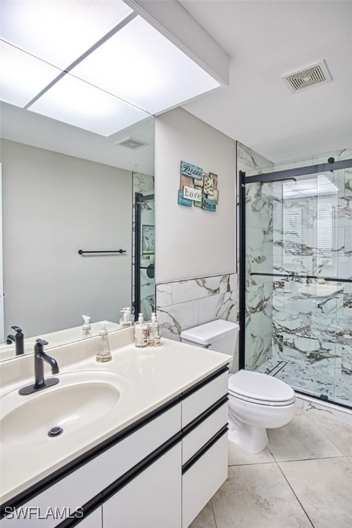 bathroom with vanity, tile patterned floors, toilet, tile walls, and a shower with shower door